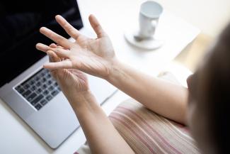 Woman holding painful finger at her desk